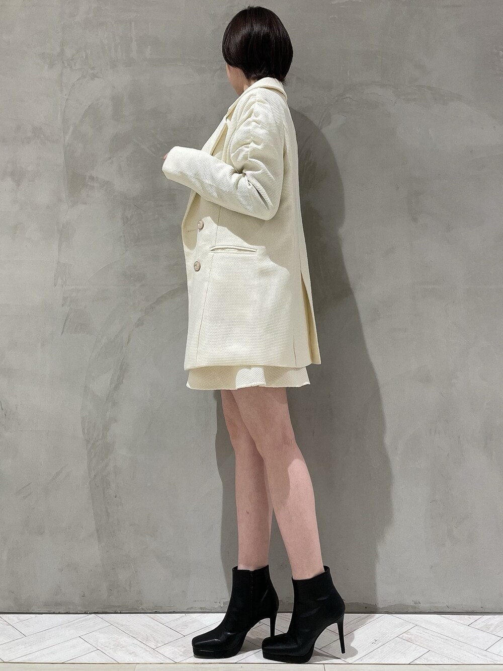 ホワイト系のテーラードジャケット、ホワイト系のスカート、ブラック系のニット/セーターを着用したレディースの冬コーディネートの2枚目の写真