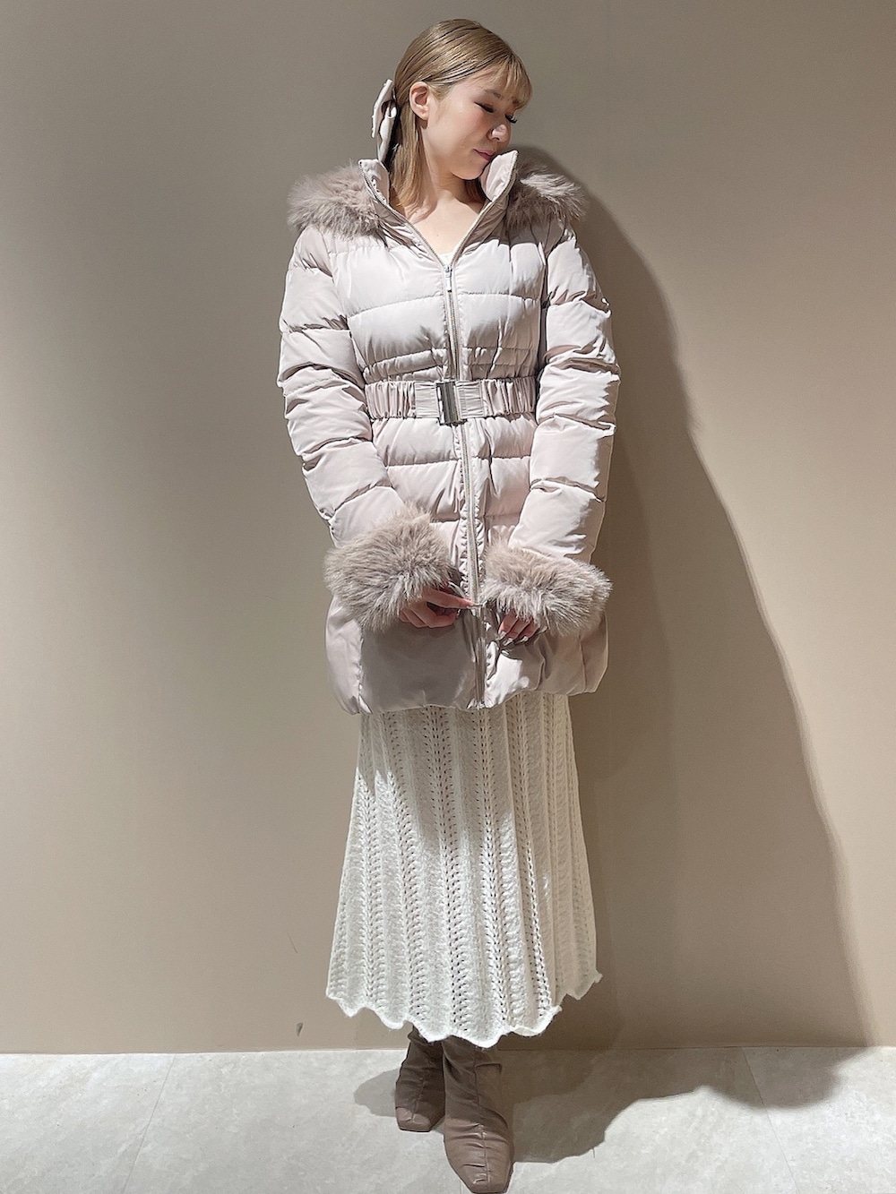 ベージュ系のブーツ、ベージュ系のダウンジャケット/コート、ホワイト系のワンピースを着用したレディースの秋コーディネートの4枚目の写真