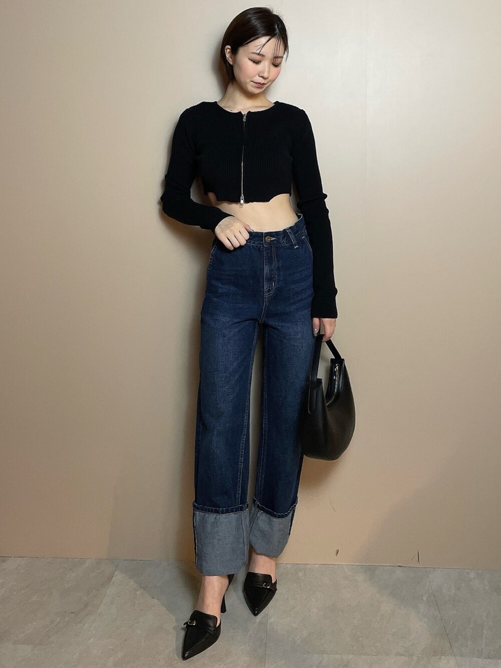 ブラック系のニット/セーター、ブルー系のデニムパンツ、ブラック系のハンドバッグを着用したレディースの冬コーディネートの3枚目の写真