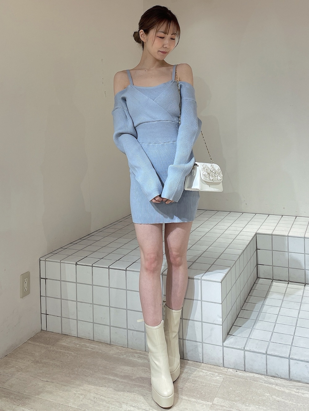 ブルー系のワンピース、ホワイト系のショルダーバッグ、ホワイト系のブーツを着用したレディースの冬コーディネートの2枚目の写真