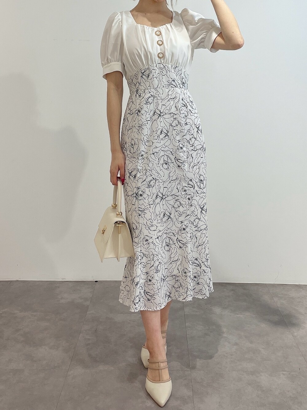 ホワイト系のワンピース、ホワイト系のハンドバッグ、ホワイト系のパンプスを着用したレディースの春コーディネートの2枚目の写真