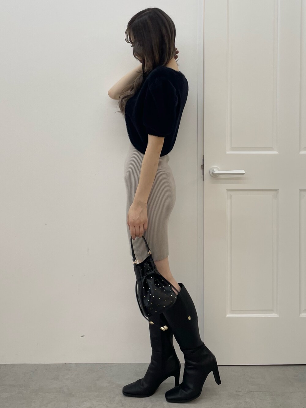 ブラック系のワンピース、ブラック系のハンドバッグ、ブラック系のブーツを着用したレディースの夏コーディネートの2枚目の写真