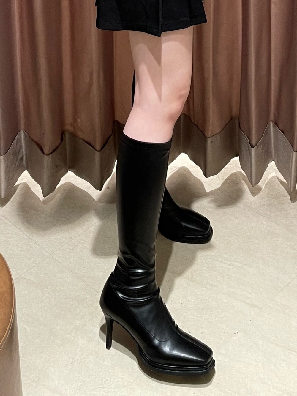 ホワイト系のニット/セーター、ブラック系のスカート、ブラック系のブーツを着用したレディースの冬コーディネートの9枚目の写真