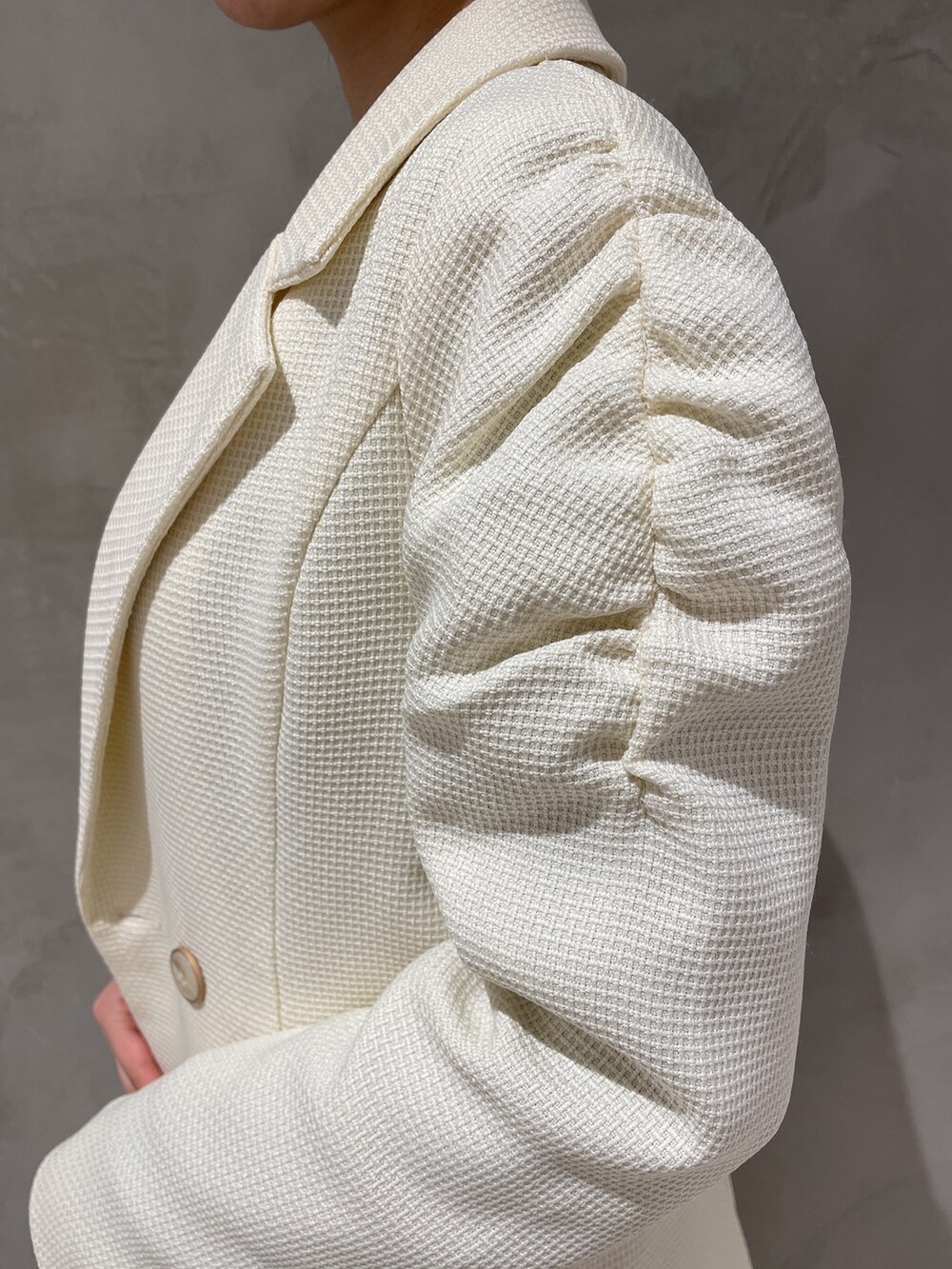 ホワイト系のテーラードジャケット、ホワイト系のスカート、ブラック系のニット/セーターを着用したレディースの冬コーディネートの5枚目の写真