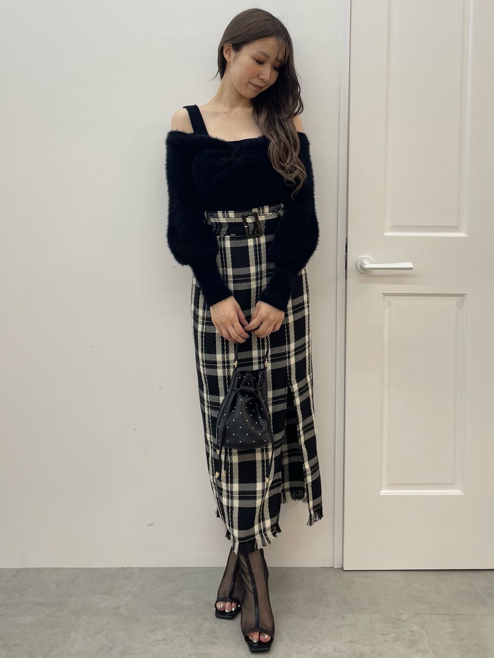 ブラック系のニット/セーター、ブラック系のスカート、ブラック系のハンドバッグを着用したレディースの夏コーディネートの2枚目の写真