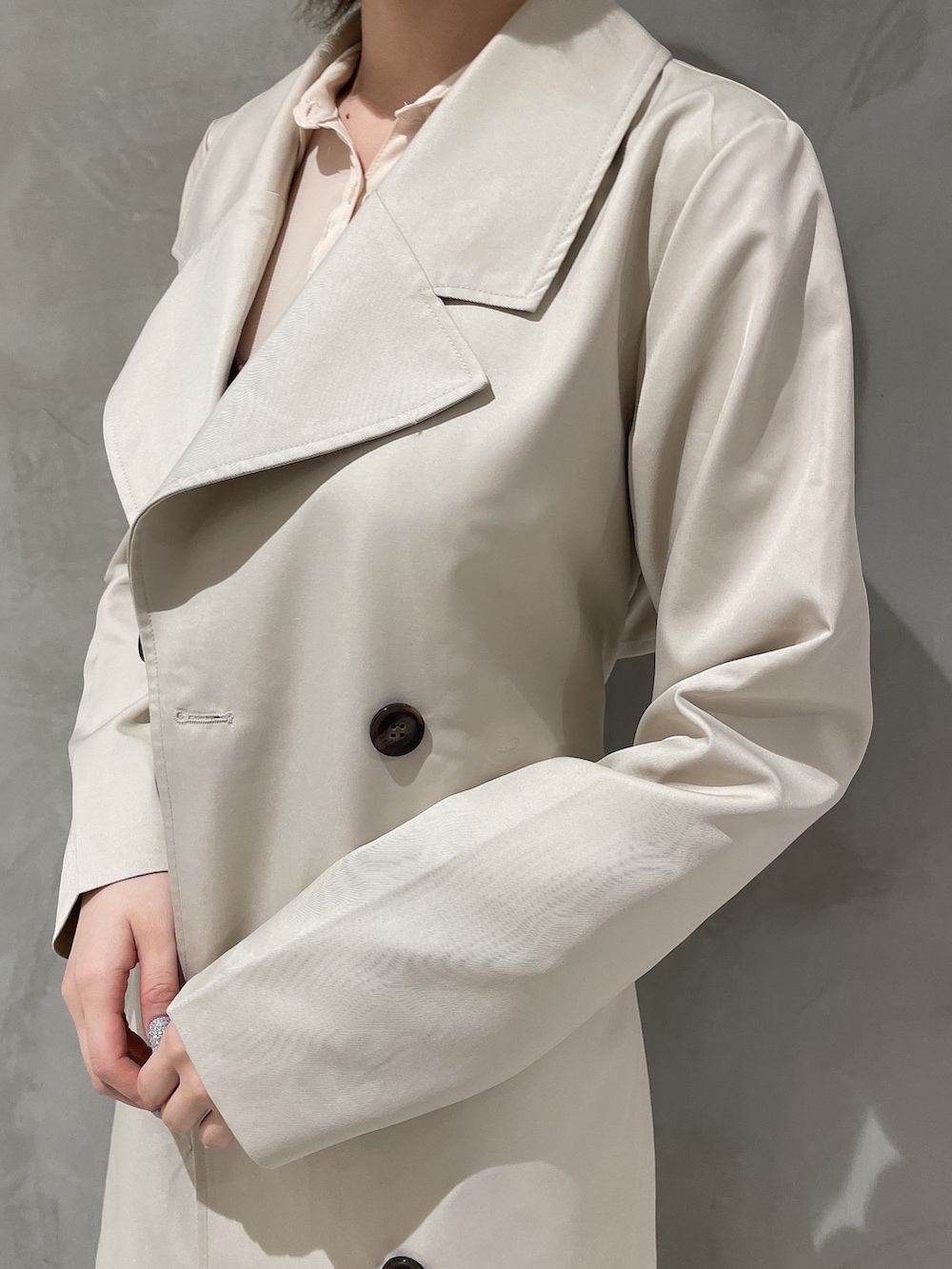 ベージュ系のトレンチコート、ブラウン系のワンピース、ホワイト系のブーツを着用したレディースの冬コーディネートの8枚目の写真