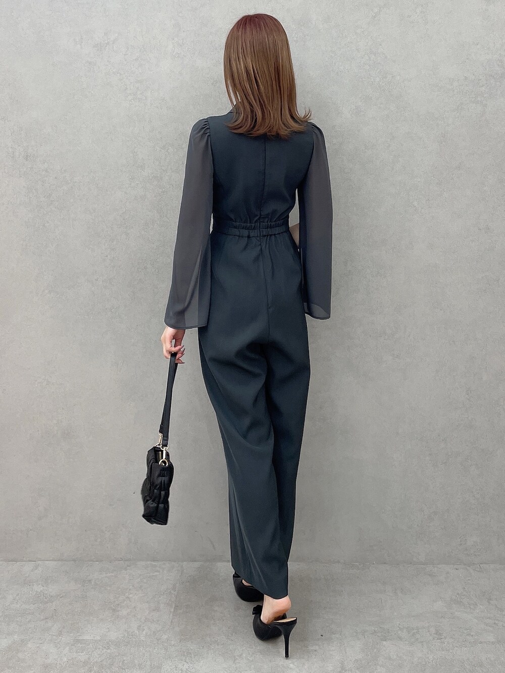 グレー系のつなぎ/オールインワン、ブラック系のハンドバッグ、ブラック系のパンプスを着用したレディースの冬コーディネートの5枚目の写真