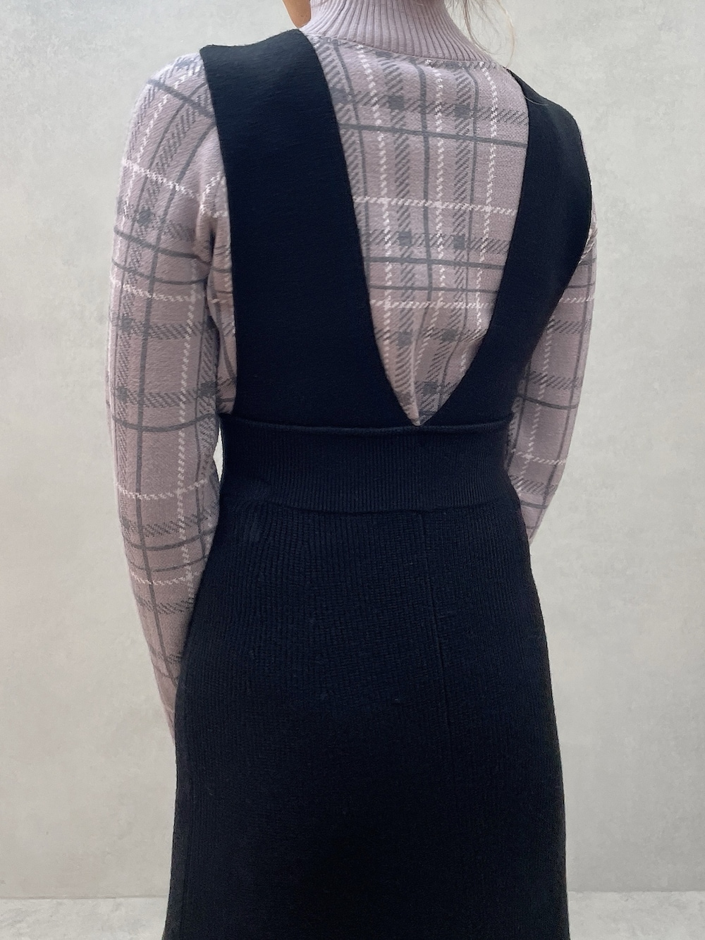 パープル系のニット/セーター、ブラック系のブーツ、ブラック系のジャンパースカートを着用したレディースの秋コーディネートの6枚目の写真