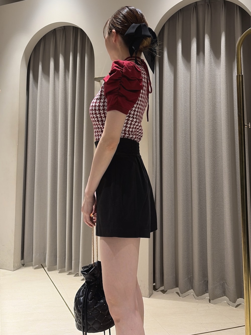 レッド系のニット/セーター、ブラック系のその他パンツ、ブラック系のハンドバッグを着用したレディースの夏コーディネートの5枚目の写真
