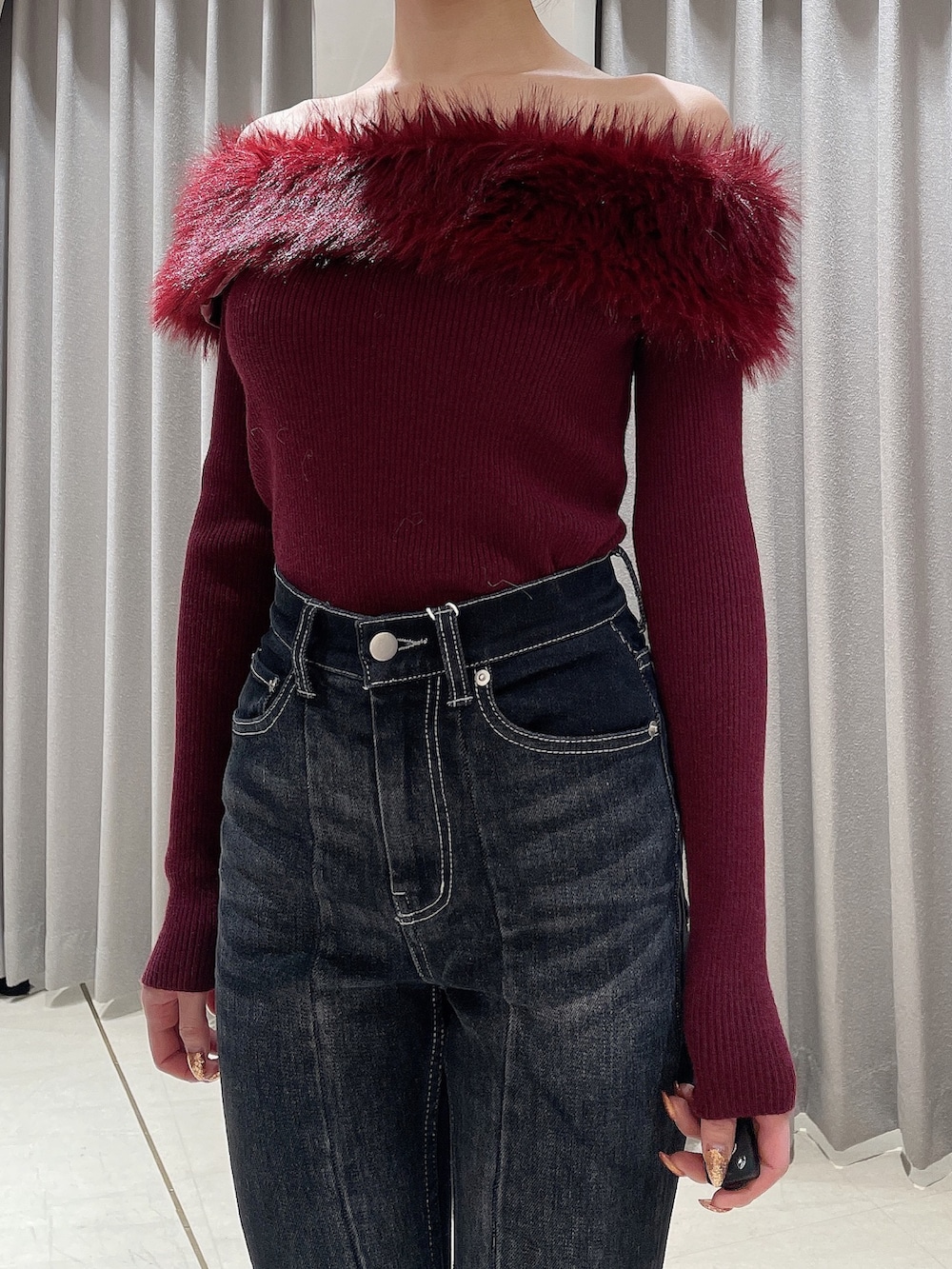 レッド系のニット/セーター、ブラック系のデニムパンツ、ブラック系のブーツを着用したレディースの秋コーディネートの7枚目の写真