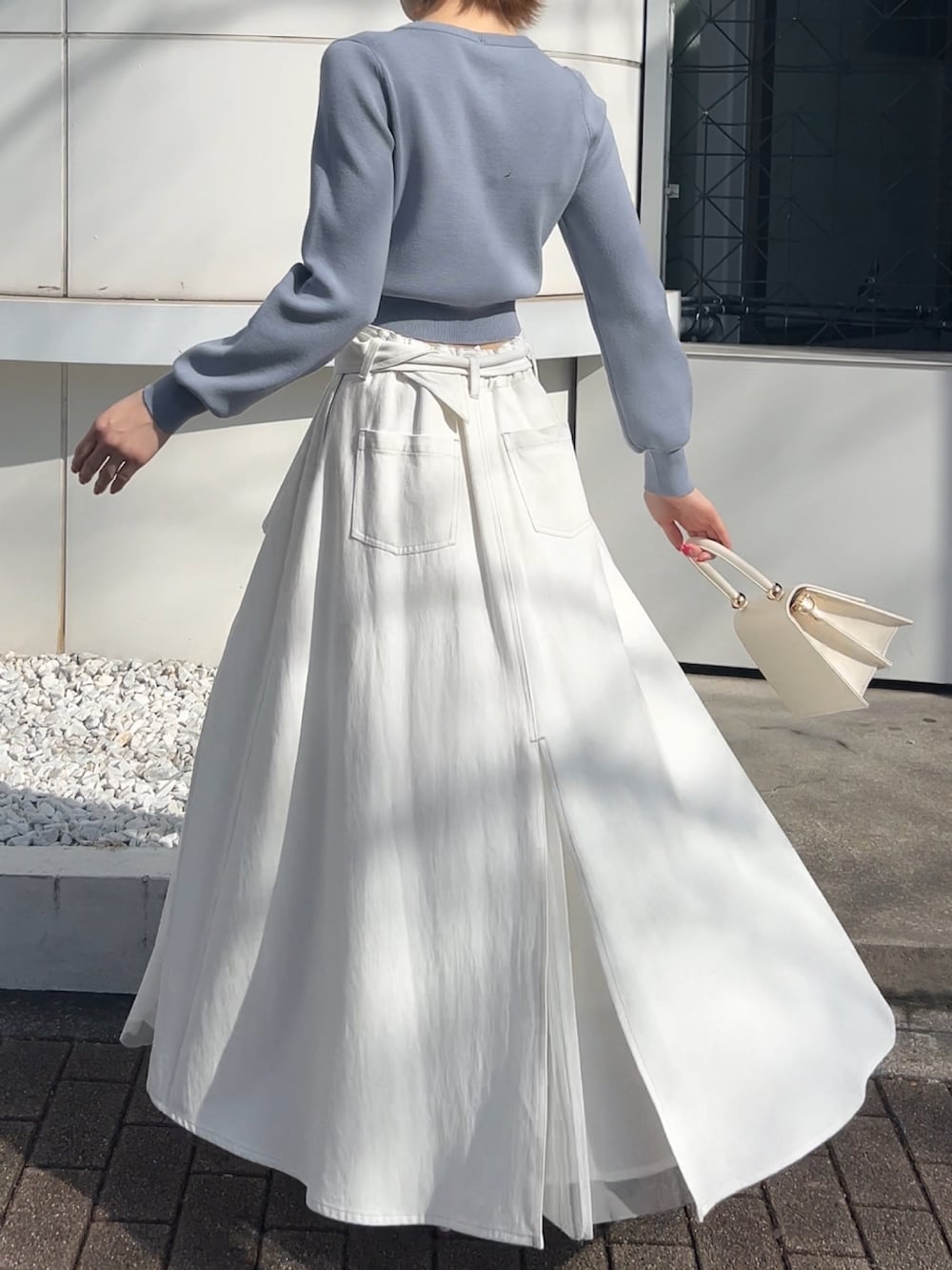 ブルー系のカーディガン/ボレロ、ホワイト系のデニムスカート、ホワイト系のハンドバッグを着用したレディースの春コーディネートの3枚目の写真