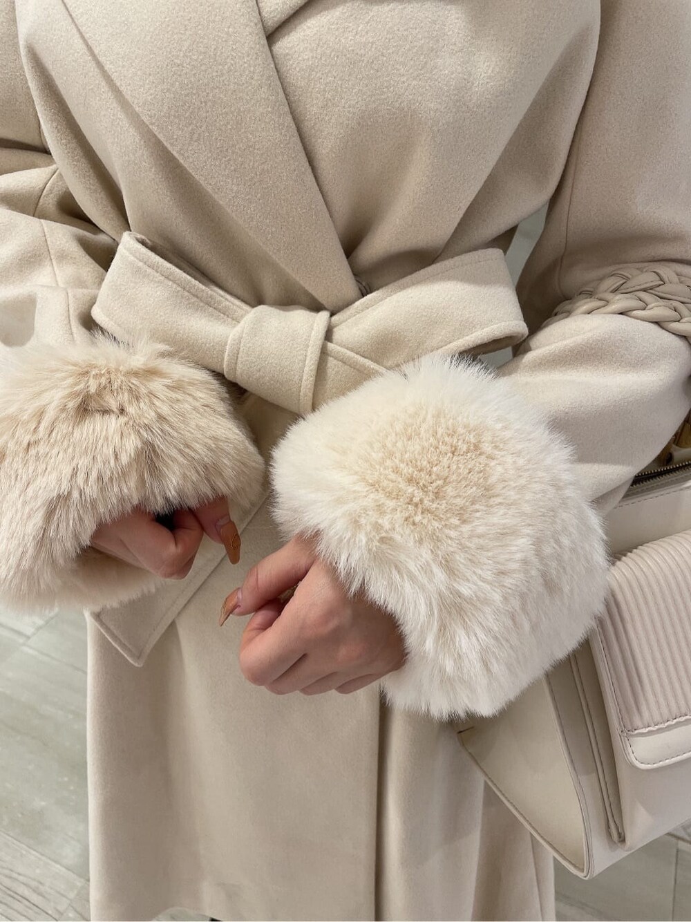 ブラック系のブーツ、ホワイト系のハンドバッグ、ホワイト系のその他アウターを着用したレディースの秋コーディネートの6枚目の写真