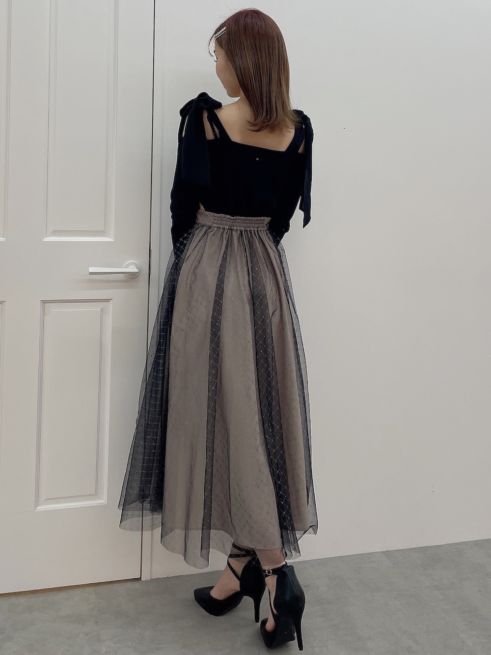 ブラック系のワンピース、ブラック系のハンドバッグ、ブラック系のパンプスを着用したレディースの冬コーディネートの4枚目の写真