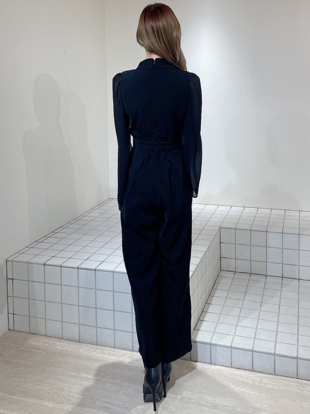 ブラック系のワンピース、ブラック系のブーツ、ブラック系のハンドバッグを着用したレディースの冬コーディネートの4枚目の写真