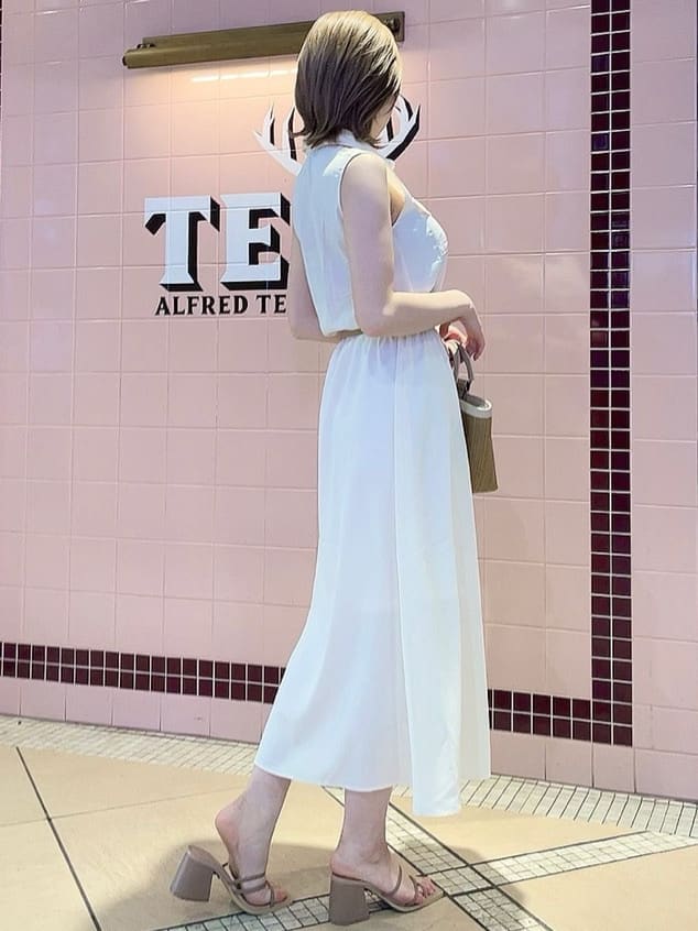 ピンク系のサンダル、ベージュ系のハンドバッグ、ホワイト系のシャツワンピースを着用したレディースの春コーディネートの2枚目の写真