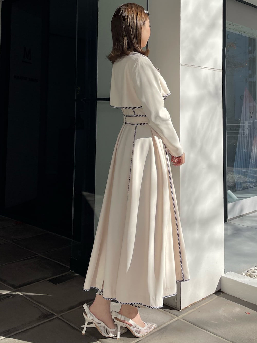 ホワイト系のトレンチコート、ブルー系のワンピース、ホワイト系のパンプスを着用したレディースの冬コーディネートの3枚目の写真