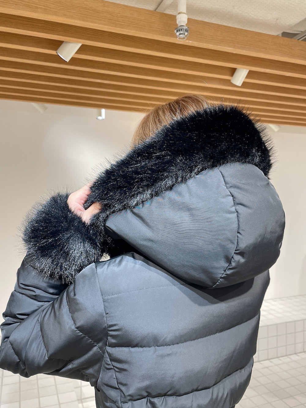 ブラック系のダウンジャケット/コート、ブラック系のワンピース、ブラック系のブーツを着用したレディースの秋コーディネートの6枚目の写真