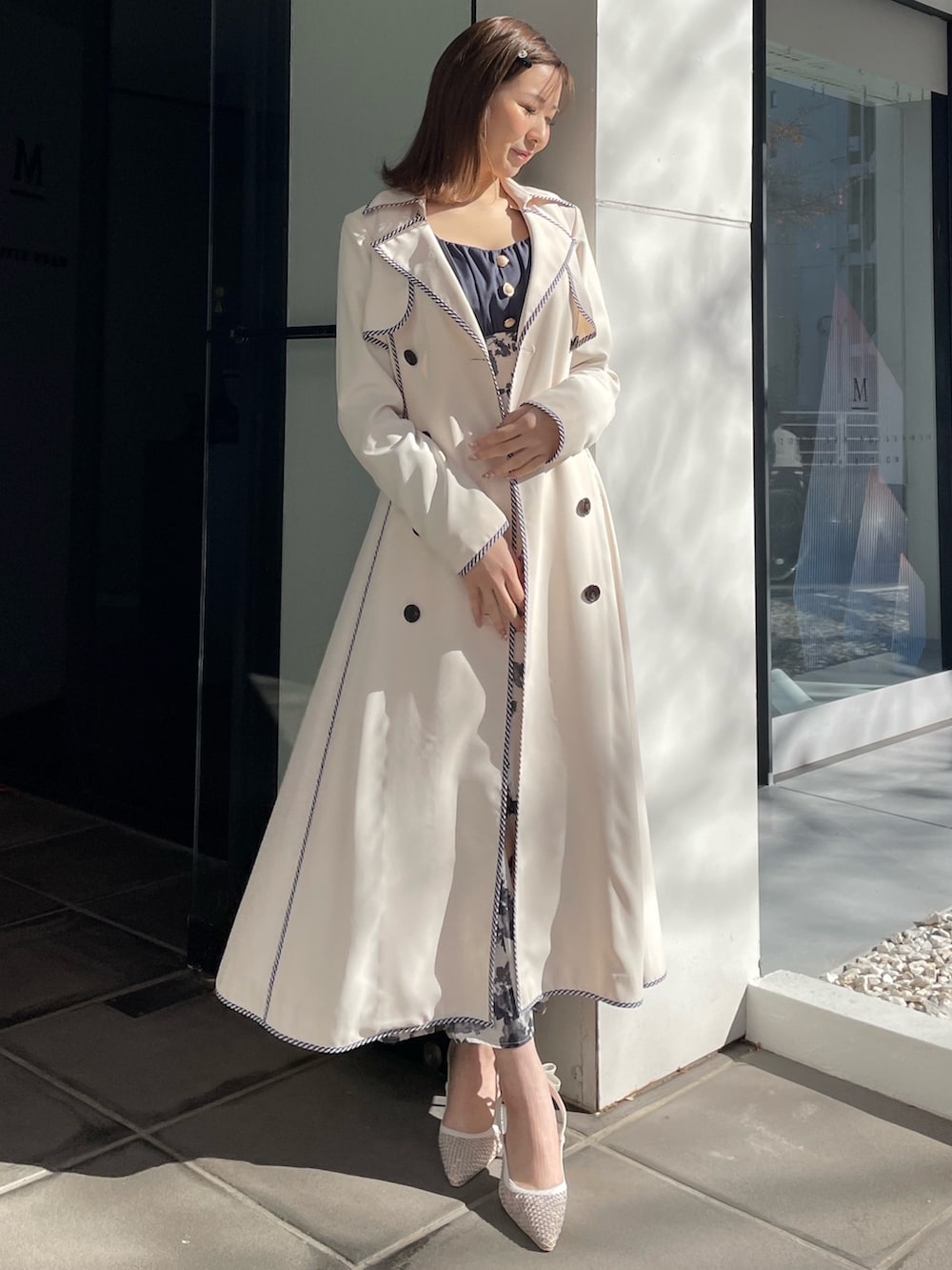 ホワイト系のトレンチコート、ブルー系のワンピース、ホワイト系のパンプスを着用したレディースの冬コーディネートの5枚目の写真