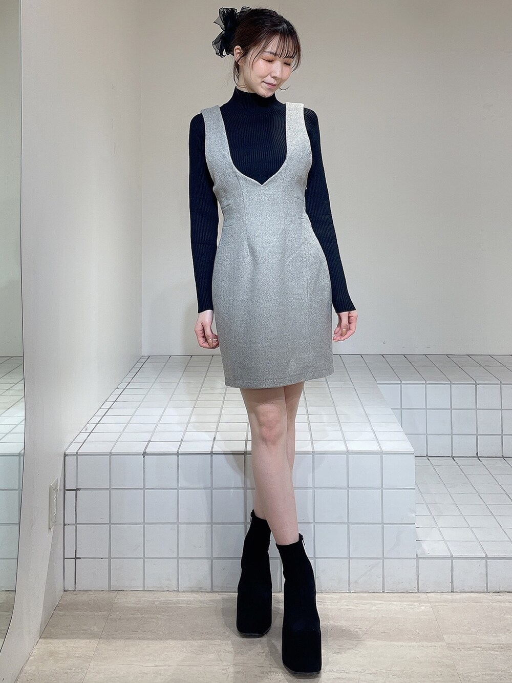 グレー系のその他アウター、グレー系のジャンパースカート、ブラック系のニット/セーターを着用したレディースの冬コーディネートの5枚目の写真