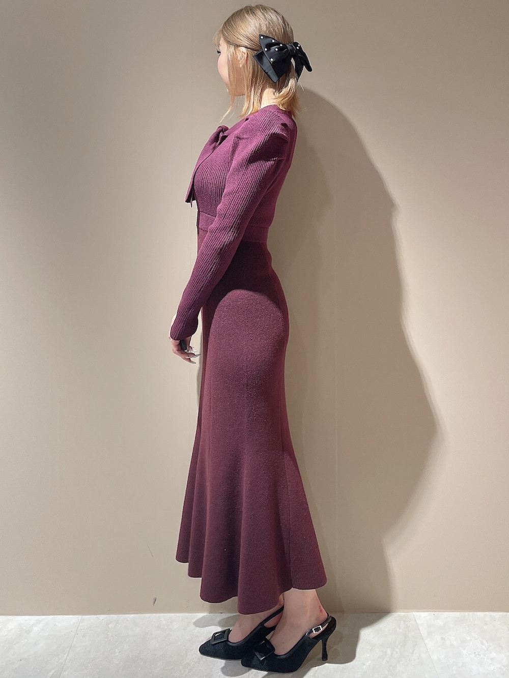 レッド系のワンピース、ブラック系のパンプス、ブラック系のダウンジャケット/コートを着用したレディースの秋コーディネートの3枚目の写真