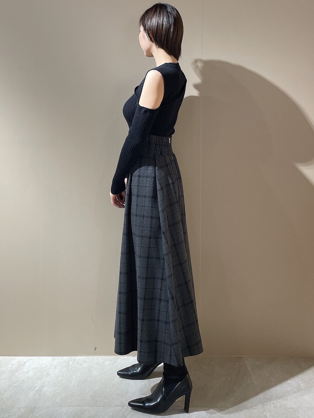 ブラック系のニット/セーター、ブラック系のスカート、ブラック系のブーツを着用したレディースの秋コーディネートの3枚目の写真