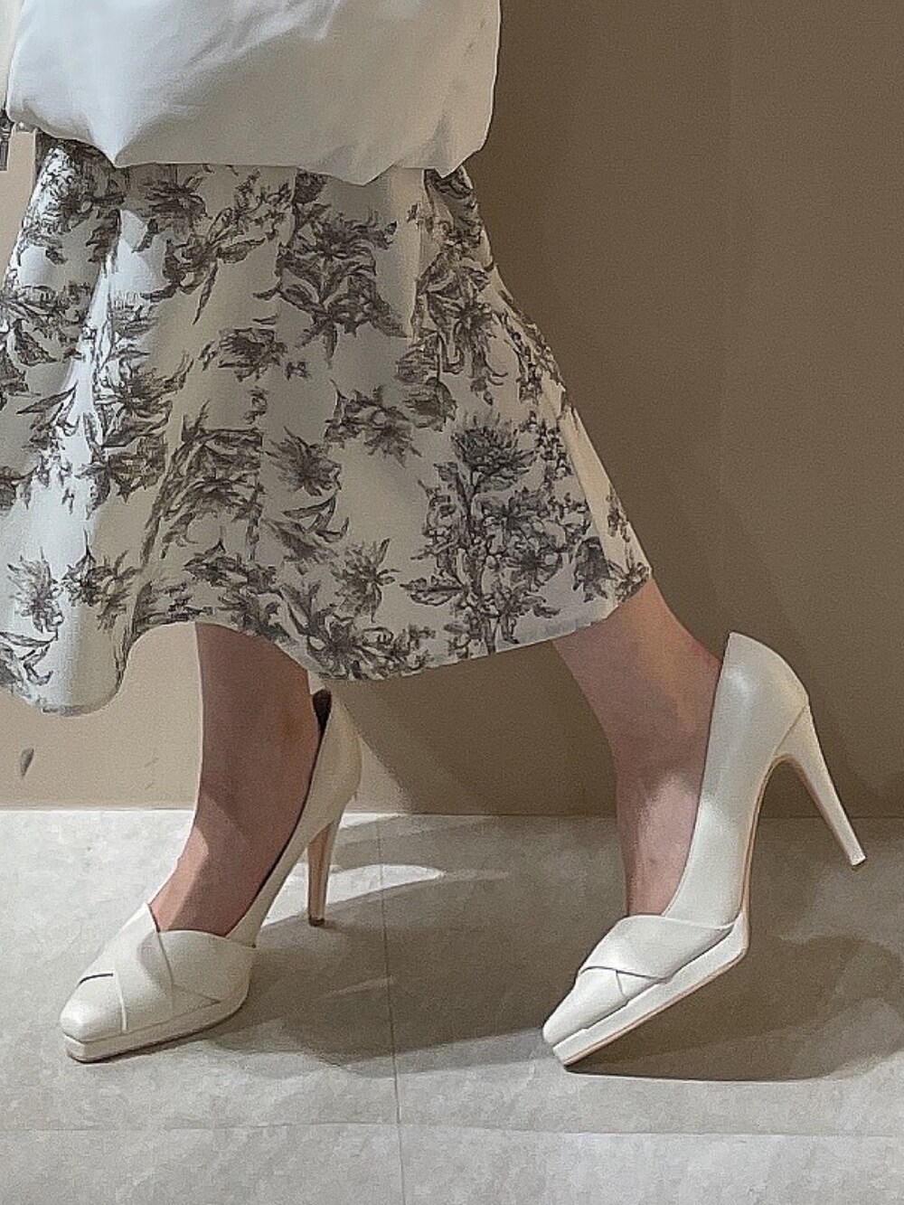 ホワイト系のダウンジャケット/コート、ホワイト系のパンプス、ベージュ系のワンピースを着用したレディースの秋コーディネートの10枚目の写真