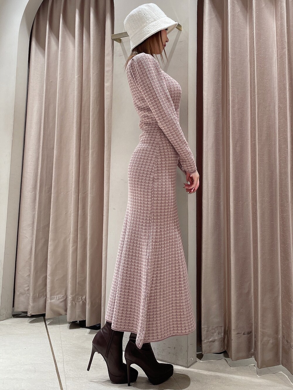 ピンク系のワンピース、ブラウン系のブーツ、ホワイト系のハットを着用したレディースの冬コーディネートの2枚目の写真