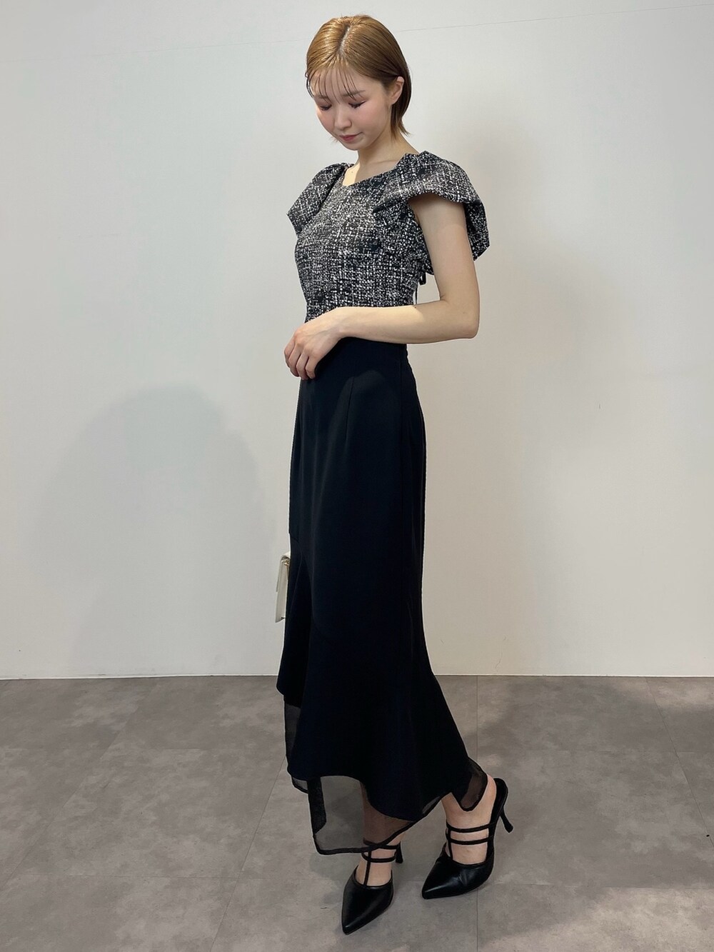 ブラック系のシャツ/ブラウス、ホワイト系のハンドバッグ、ブラック系のパンプスを着用したレディースの春コーディネートの3枚目の写真