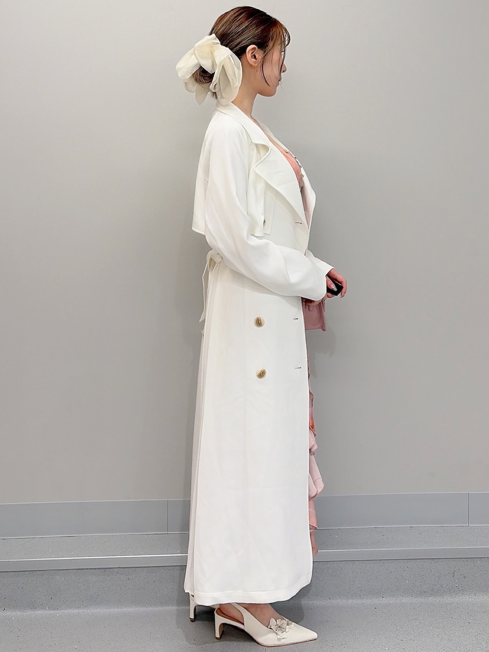 ホワイト系のトレンチコート、ピンク系のショルダーバッグ、オレンジ系のワンピースを着用したレディースの冬コーディネートの2枚目の写真