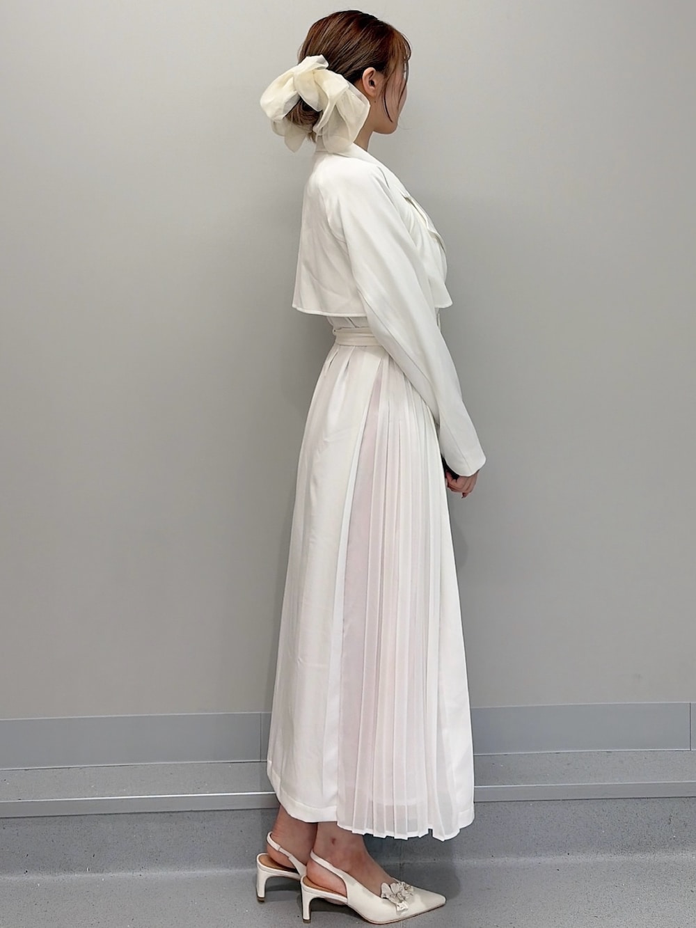 ホワイト系のトレンチコート、ピンク系のショルダーバッグ、オレンジ系のワンピースを着用したレディースの冬コーディネートの5枚目の写真