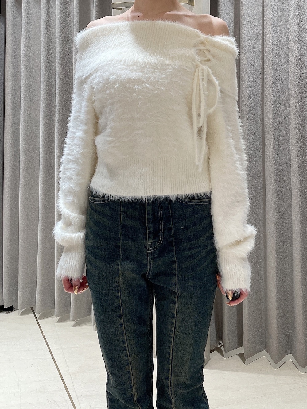 ホワイト系のニット/セーター、ブルー系のデニムパンツ、ブラック系のブーツを着用したレディースの秋コーディネートの5枚目の写真