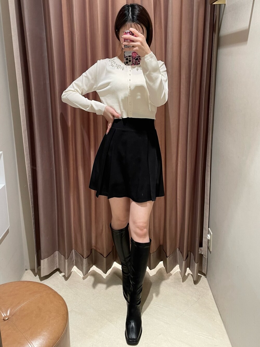 ホワイト系のカーディガン/ボレロ、ブラック系のスカート、ブラック系のブーツを着用したレディースの冬コーディネートの2枚目の写真