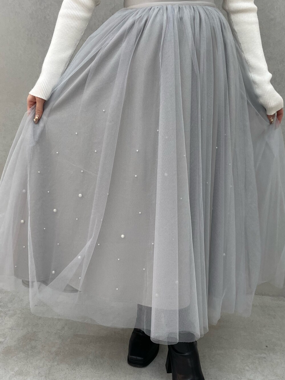 ホワイト系のニット/セーター、グレー系のスカート、ブラック系のブーツを着用したレディースの冬コーディネートの6枚目の写真