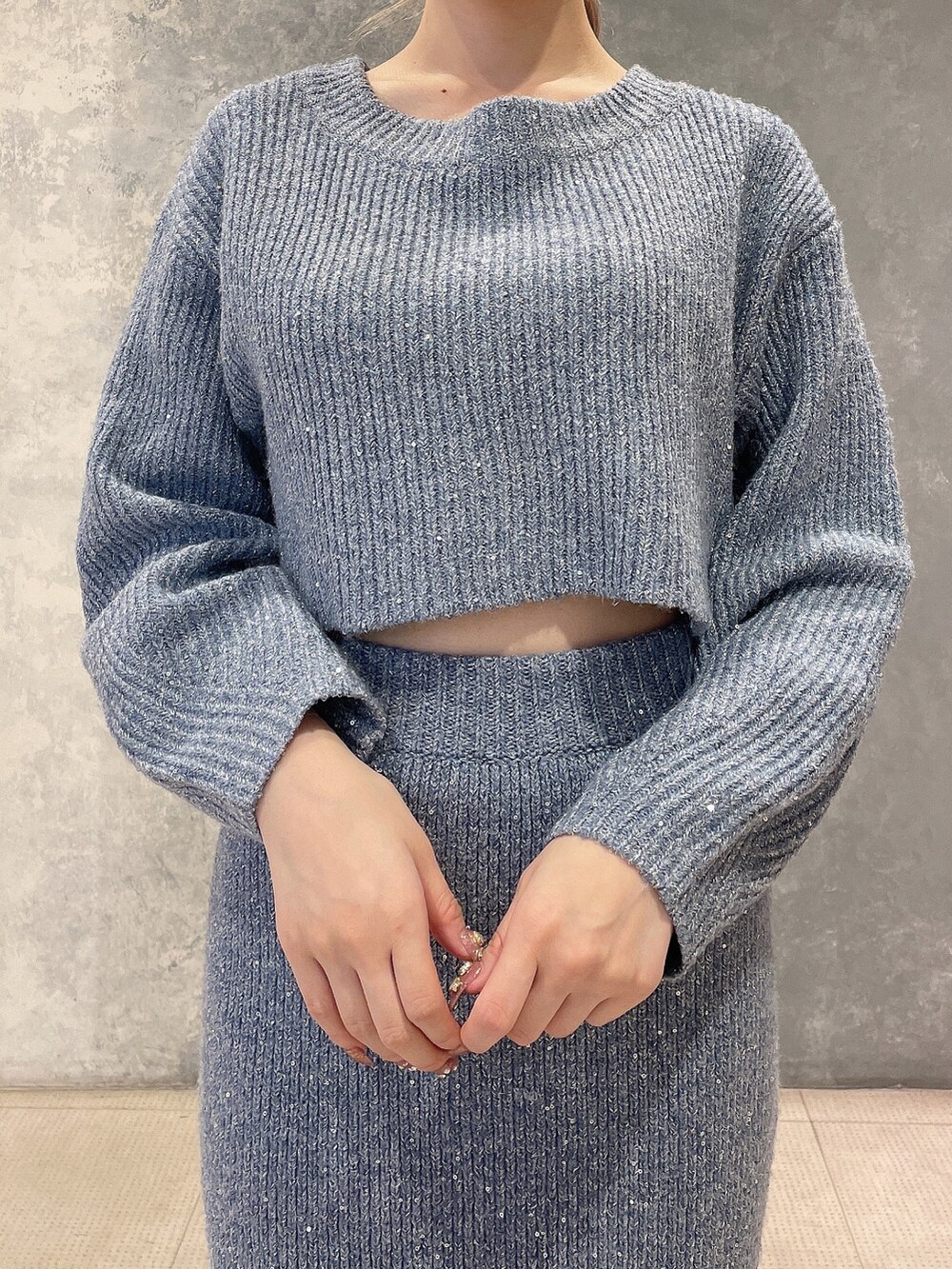 ブルー系のニット/セーター、ブルー系のスカート、ブラック系のブーツを着用したレディースの秋コーディネートの6枚目の写真