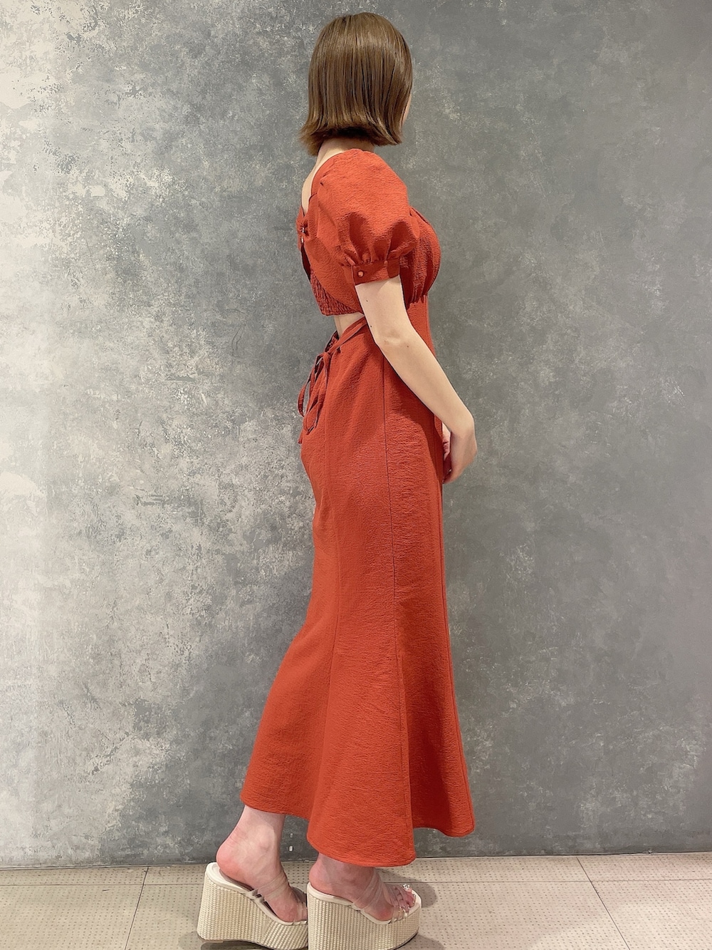 オレンジ系のワンピース、ホワイト系のサンダルを着用したレディースの春コーディネートの4枚目の写真