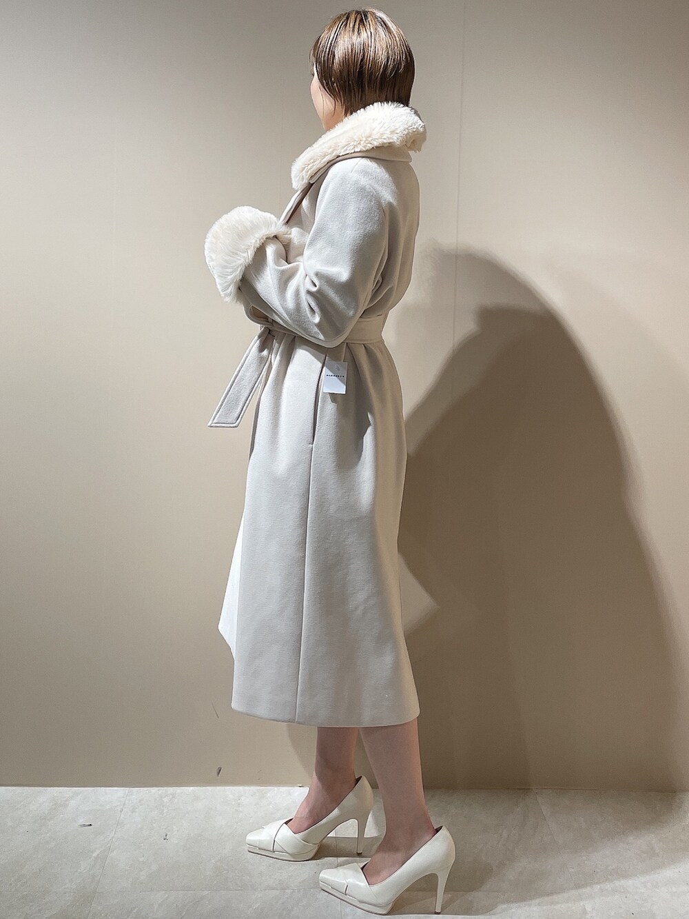 グレー系のワンピース、ホワイト系のパンプス、ホワイト系のチェスターコートを着用したレディースの秋コーディネートの4枚目の写真