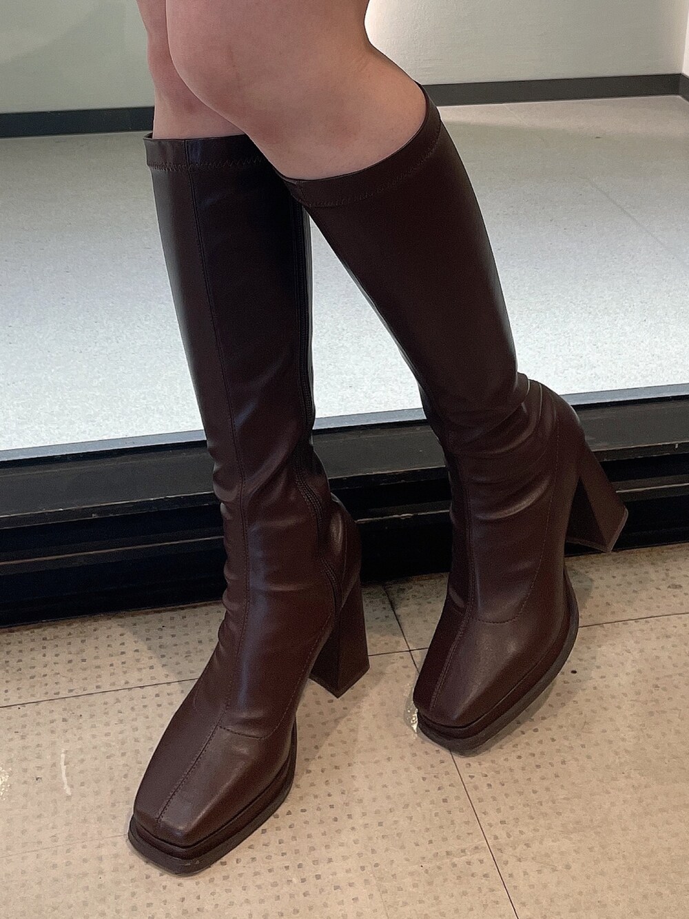 パープル系のニット/セーター、ホワイト系のスカート、ブラウン系のブーツを着用したレディースの冬コーディネートの7枚目の写真