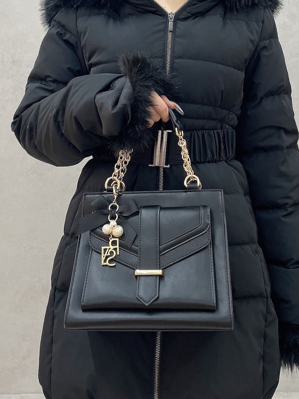 ブラック系のダウンジャケット/コート、パープル系のワンピース、ブラック系のハンドバッグを着用したレディースの秋コーディネートの7枚目の写真