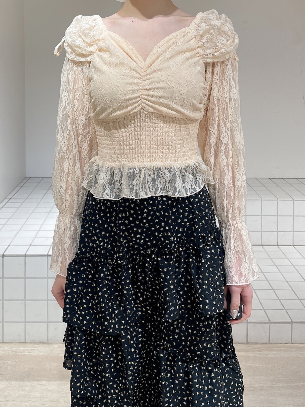 オレンジ系のシャツ/ブラウス、ブラック系のスカート、ホワイト系のパンプスを着用したレディースの春コーディネートの6枚目の写真