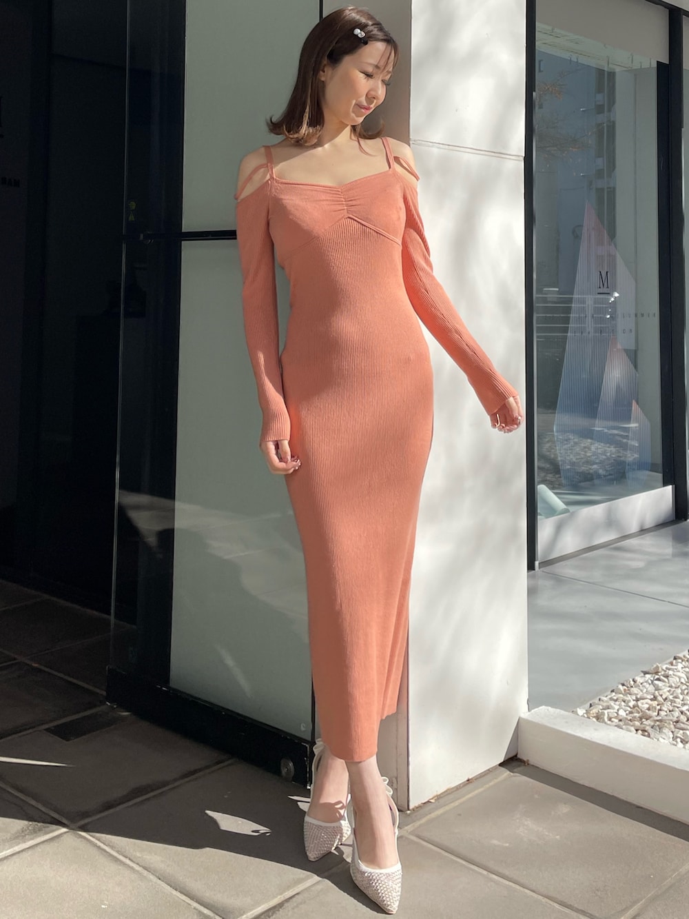オレンジ系のワンピース、ホワイト系のパンプスを着用したレディースの冬コーディネートの2枚目の写真