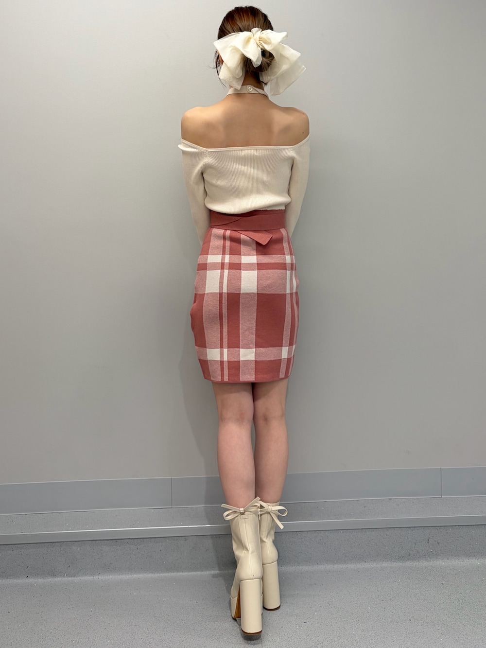 オレンジ系のワンピース、ホワイト系のブーツ、ホワイト系のバレッタ/ヘアクリップを着用したレディースの冬コーディネートの4枚目の写真