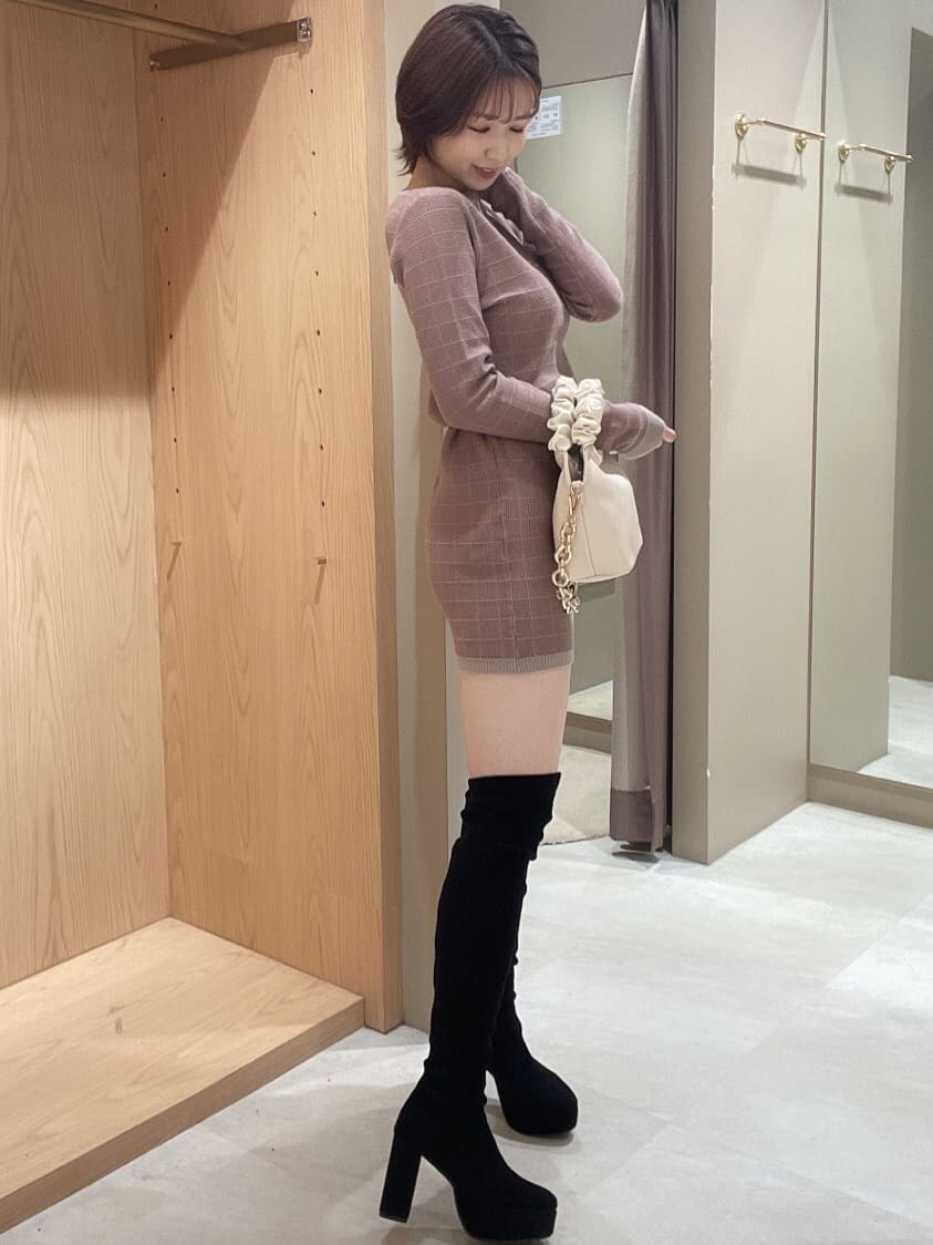 ブラック系のブーツ、ベージュ系のワンピース、ホワイト系のハンドバッグを着用したレディースの秋コーディネートの2枚目の写真