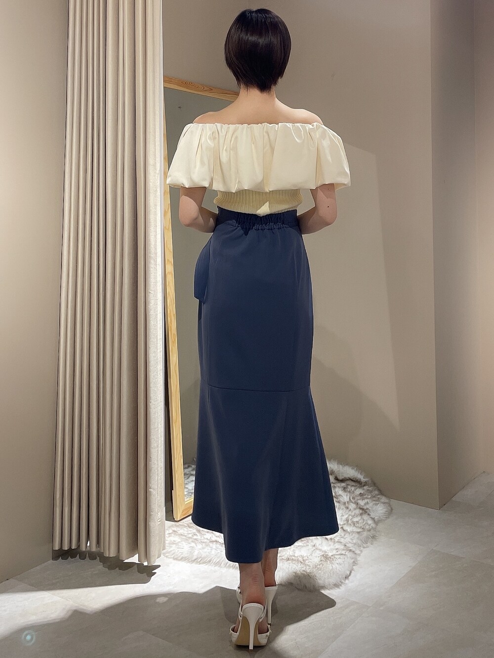 ホワイト系のニット/セーター、ブルー系のスカート、ホワイト系のパンプスを着用したレディースの春コーディネートの3枚目の写真