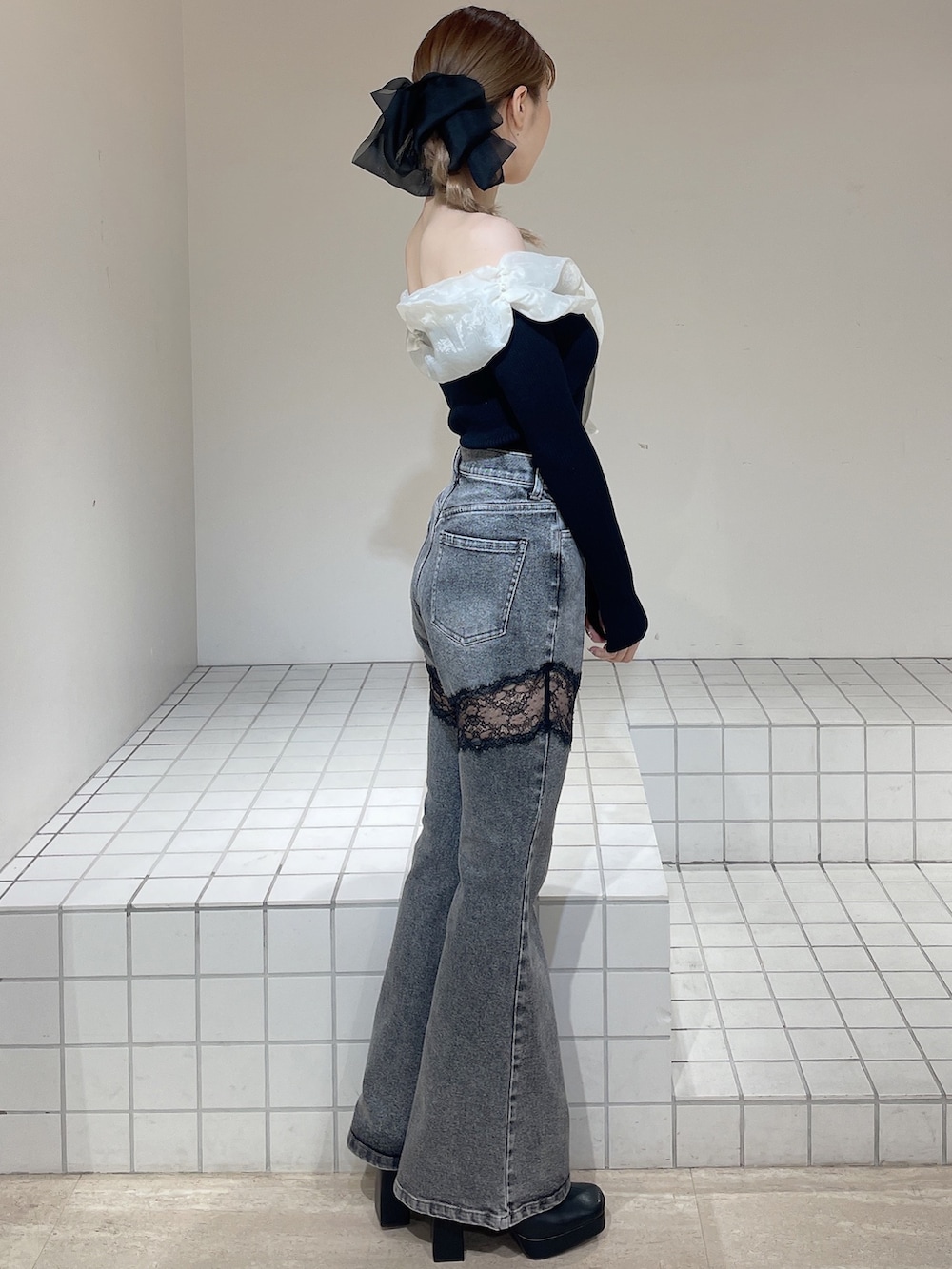 ブラック系のニット/セーター、グレー系のデニムパンツ、ブラック系のブーツを着用したレディースの春コーディネートの2枚目の写真