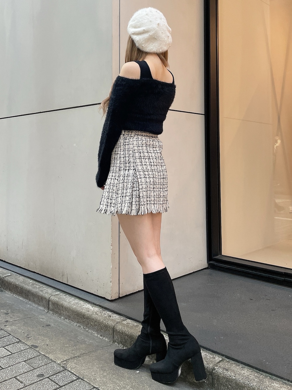 ブラック系のブーツ、ホワイト系のスカート、ブラック系のニット/セーターを着用したレディースの秋コーディネートの2枚目の写真