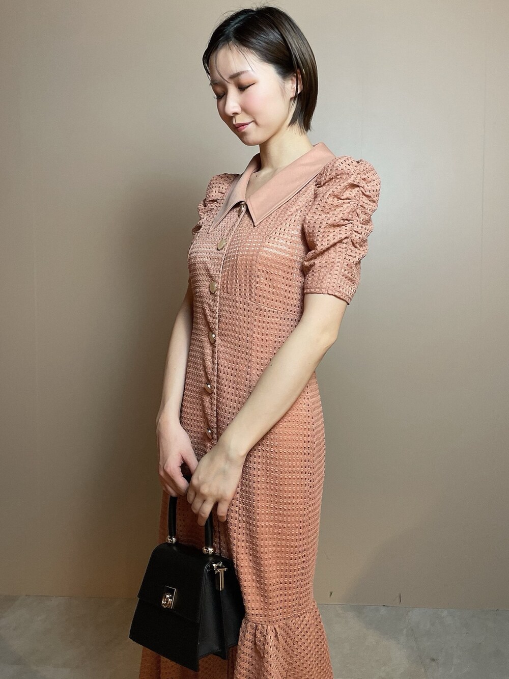 オレンジ系のワンピース、ブラック系のハンドバッグ、ブラック系のパンプスを着用したレディースの冬コーディネートの7枚目の写真