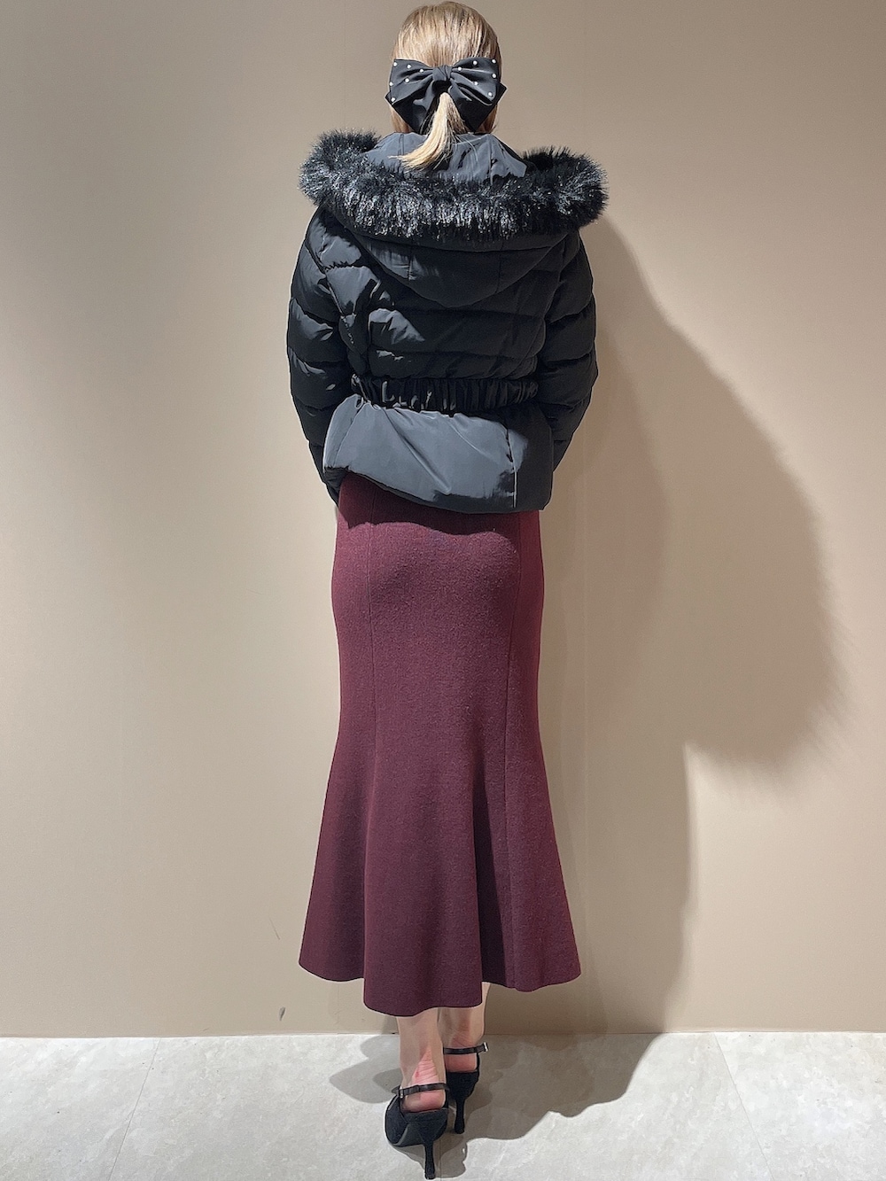 レッド系のワンピース、ブラック系のパンプス、ブラック系のダウンジャケット/コートを着用したレディースの秋コーディネートの7枚目の写真