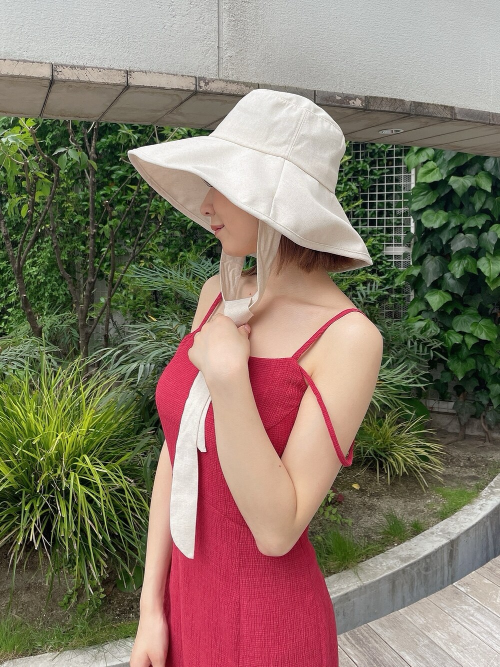 レッド系のワンピース、ホワイト系のサンダル、ホワイト系のハットを着用したレディースの夏コーディネートの5枚目の写真