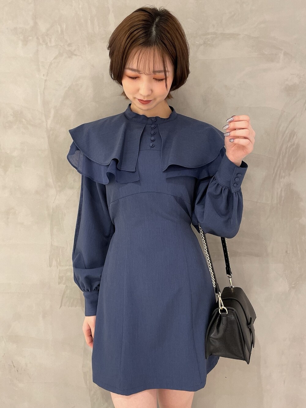 ブラック系のハンドバッグ、ブラック系のブーツ、ブルー系のワンピースを着用したレディースの冬コーディネートの4枚目の写真