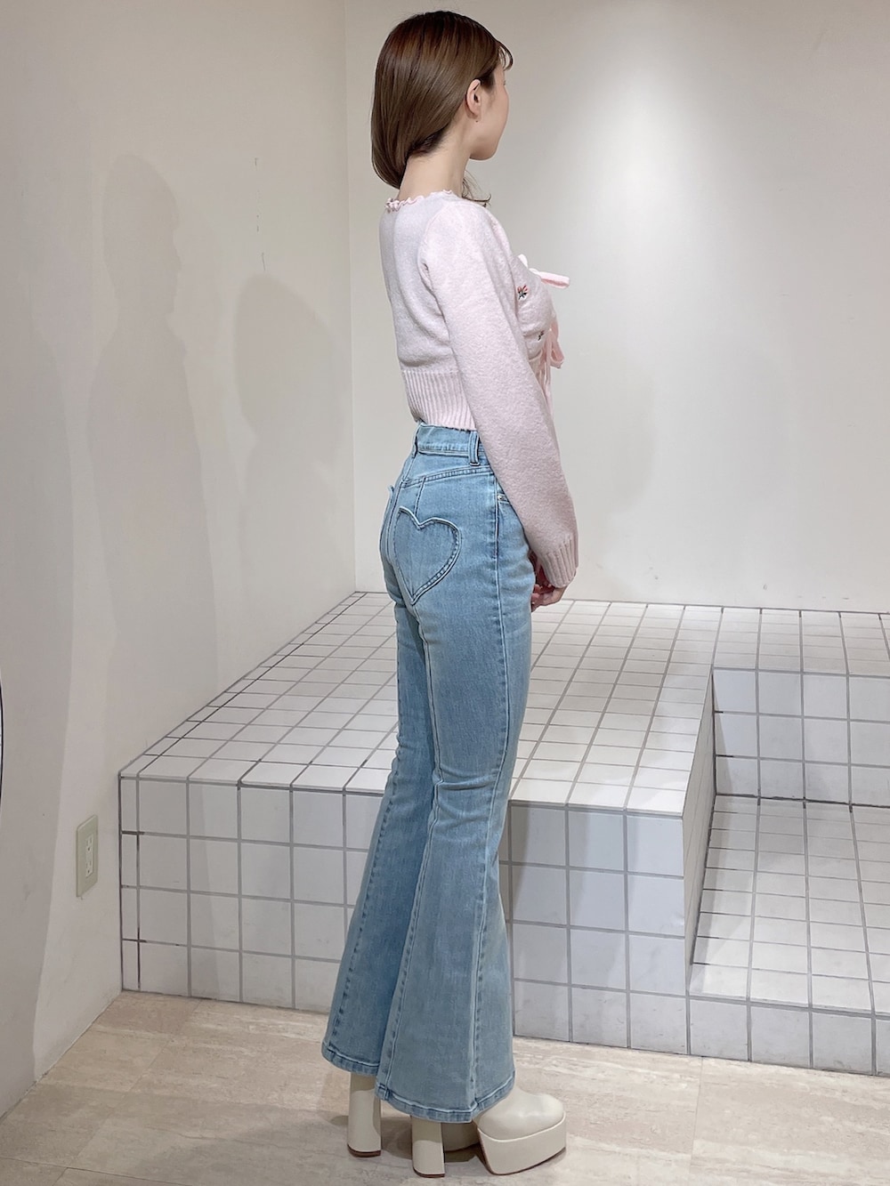 ピンク系のニット/セーター、ブルー系のデニムパンツ、ホワイト系のブーツを着用したレディースの冬コーディネートの3枚目の写真